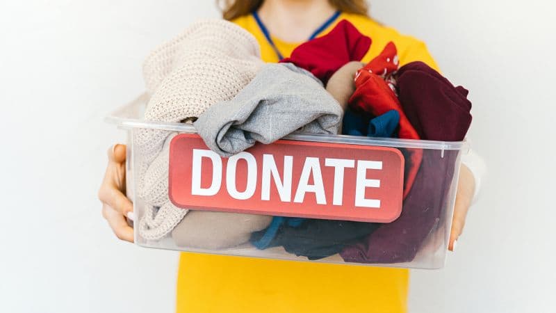 Woman holding a stack of folded clothes ready to donate